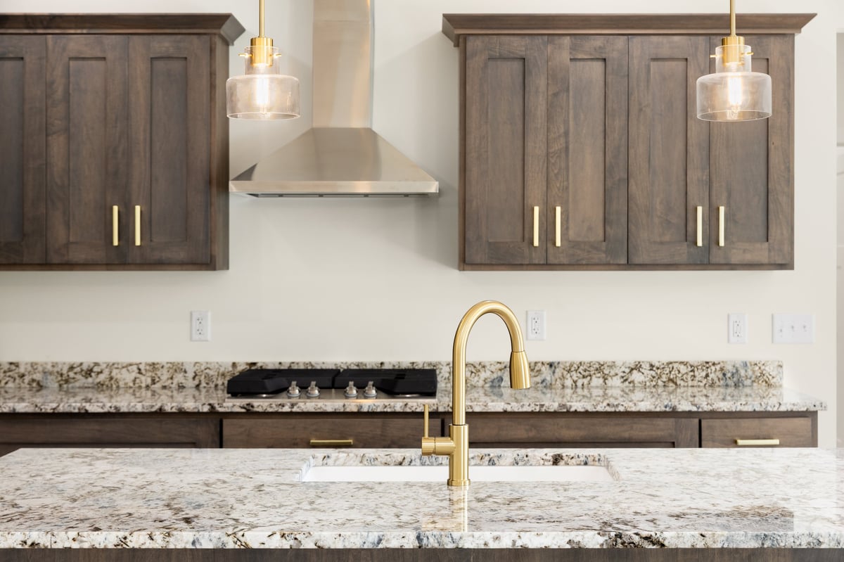 Granite countertop with dark cabinets and gold fixtures in a kitchen