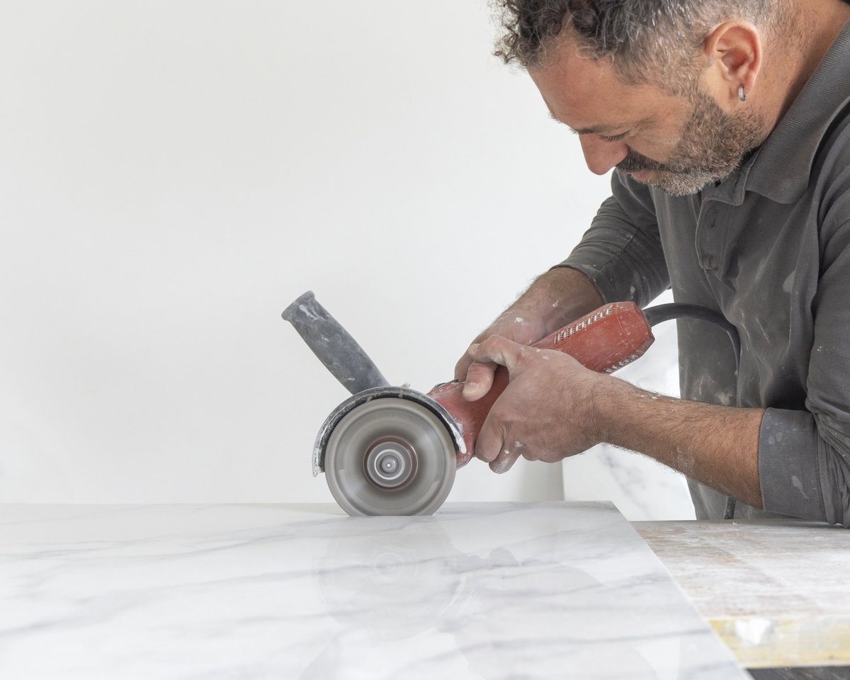 Craftman cutting gray marble tile using angle grinder